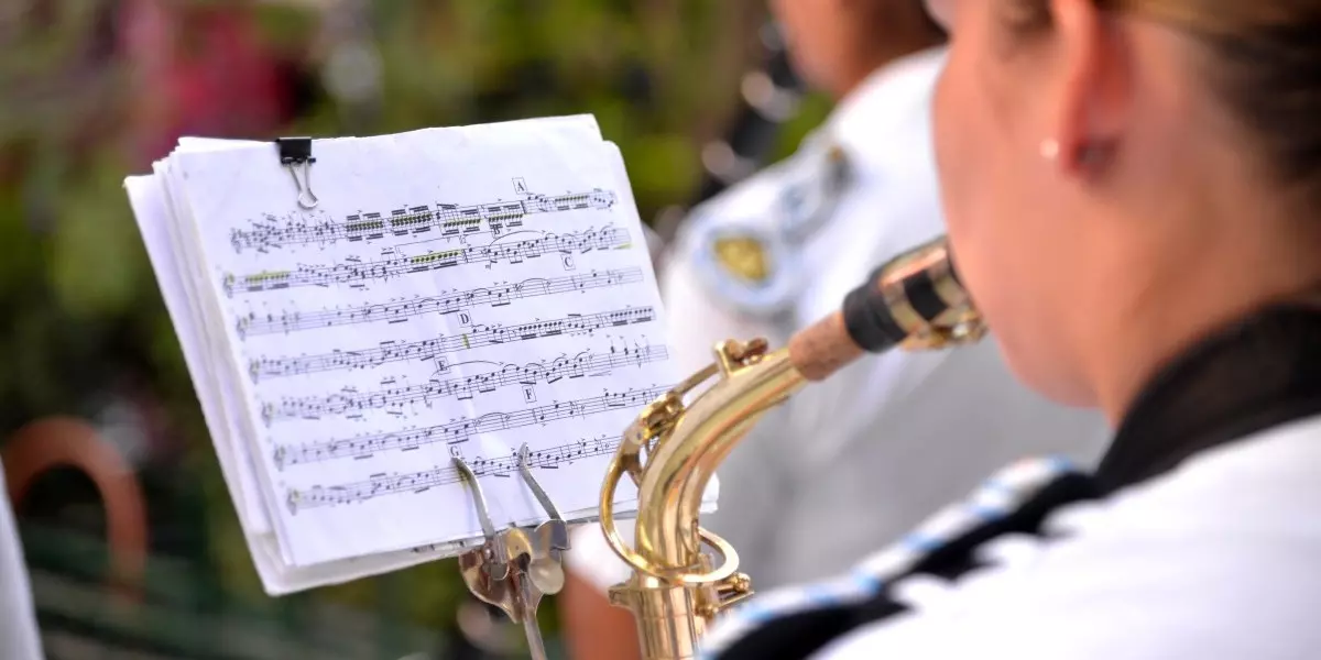 Une femme dans une fanfare jouant du saxophone et lisant une partition.